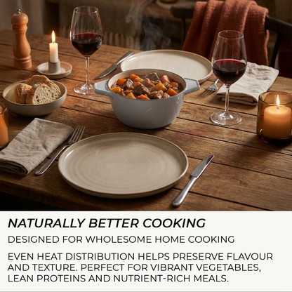 Dinner table set with a bowl of stew, bread, wine glasses, and candles on a wooden surface.