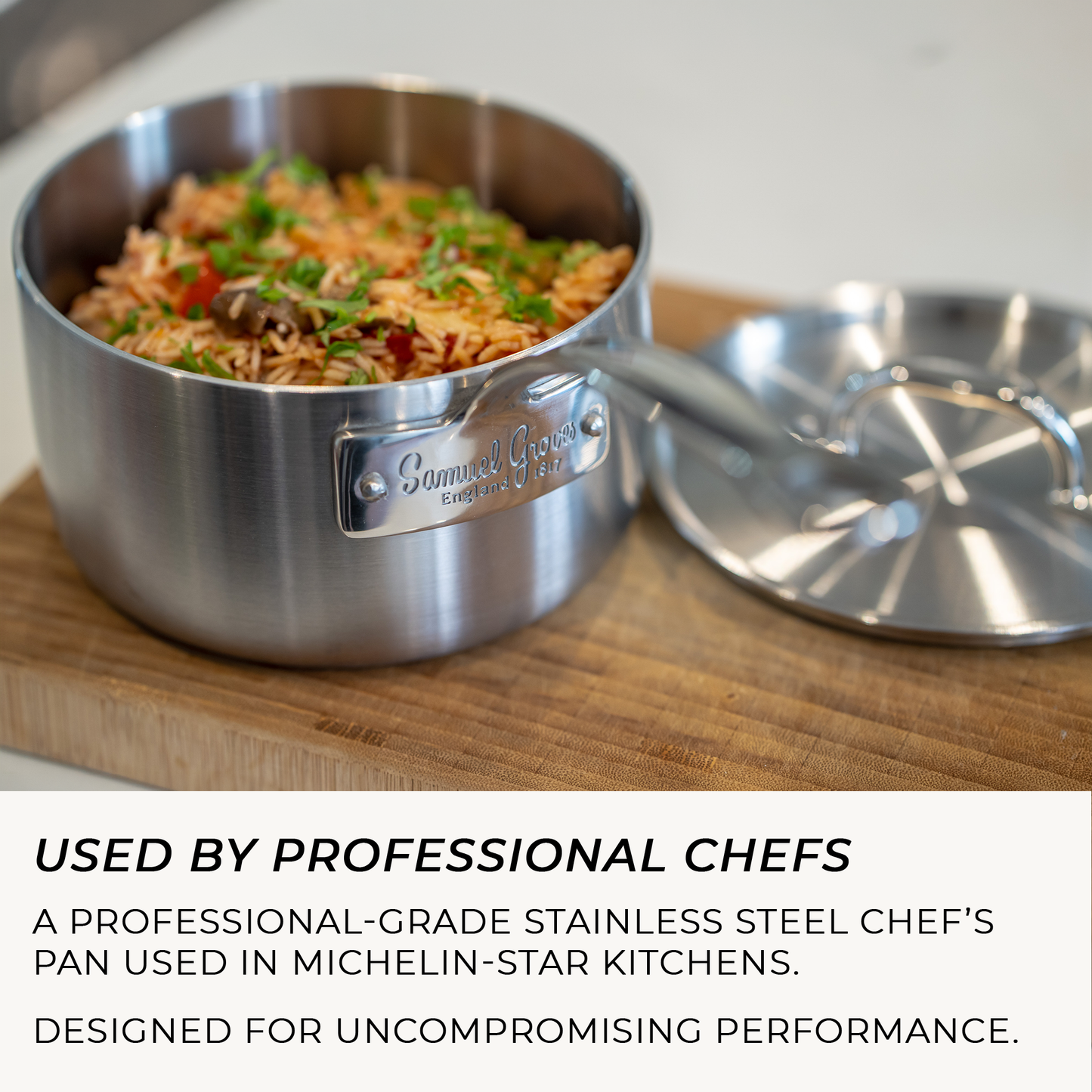 Stainless steel chef's pan with food on a wooden surface, featuring the brand name.