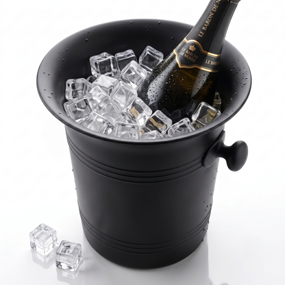 A matte black champagne bucket filled with clear ice cubes, with a chilled champagne bottle placed inside and two loose ice cubes on the white surface beside it.