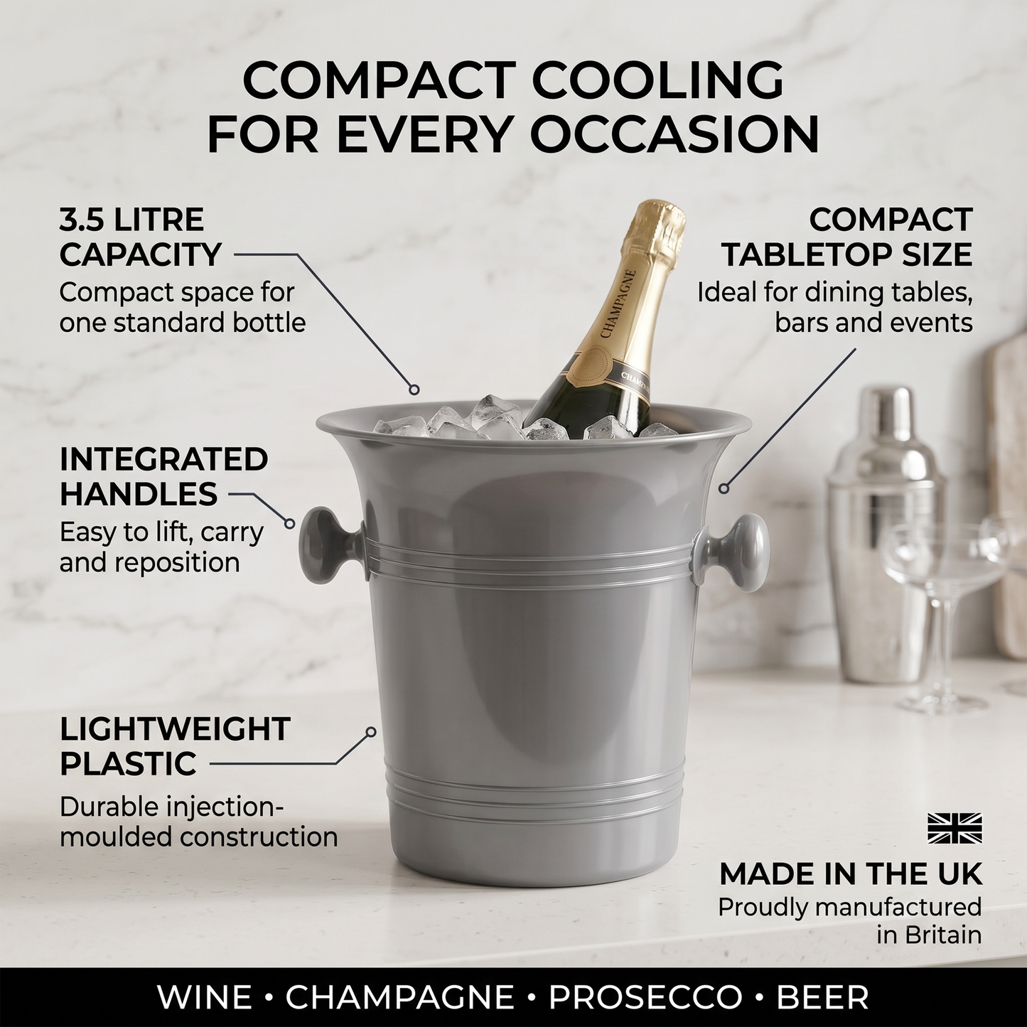 A gray compact ice bucket with a champagne bottle inside, shown on a light marble surface with callout text describing its features: 3.5 litre capacity, compact tabletop size, integrated handles, lightweight plastic construction, and made in Britain.