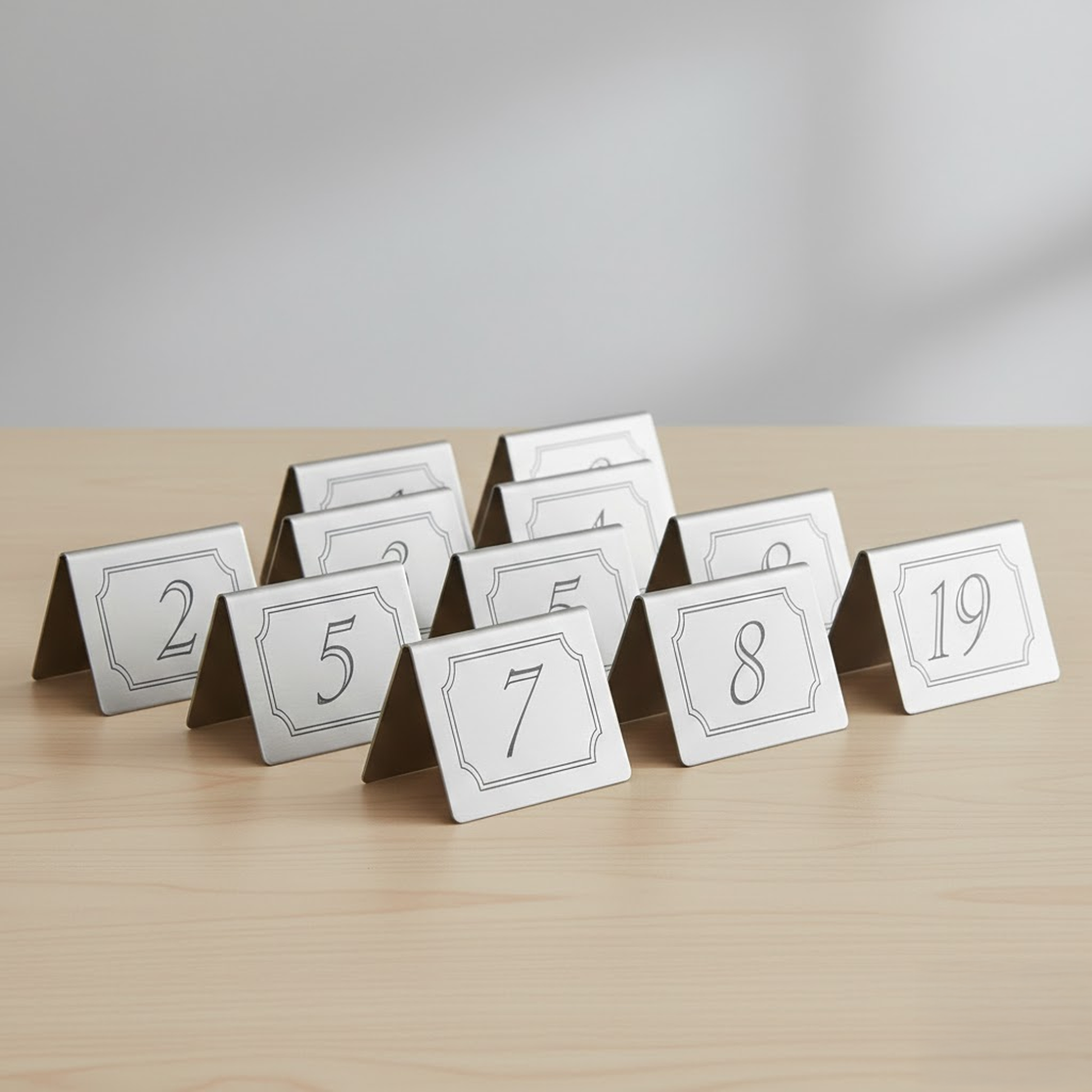 Stainless steel table number held in hand showing size and scale